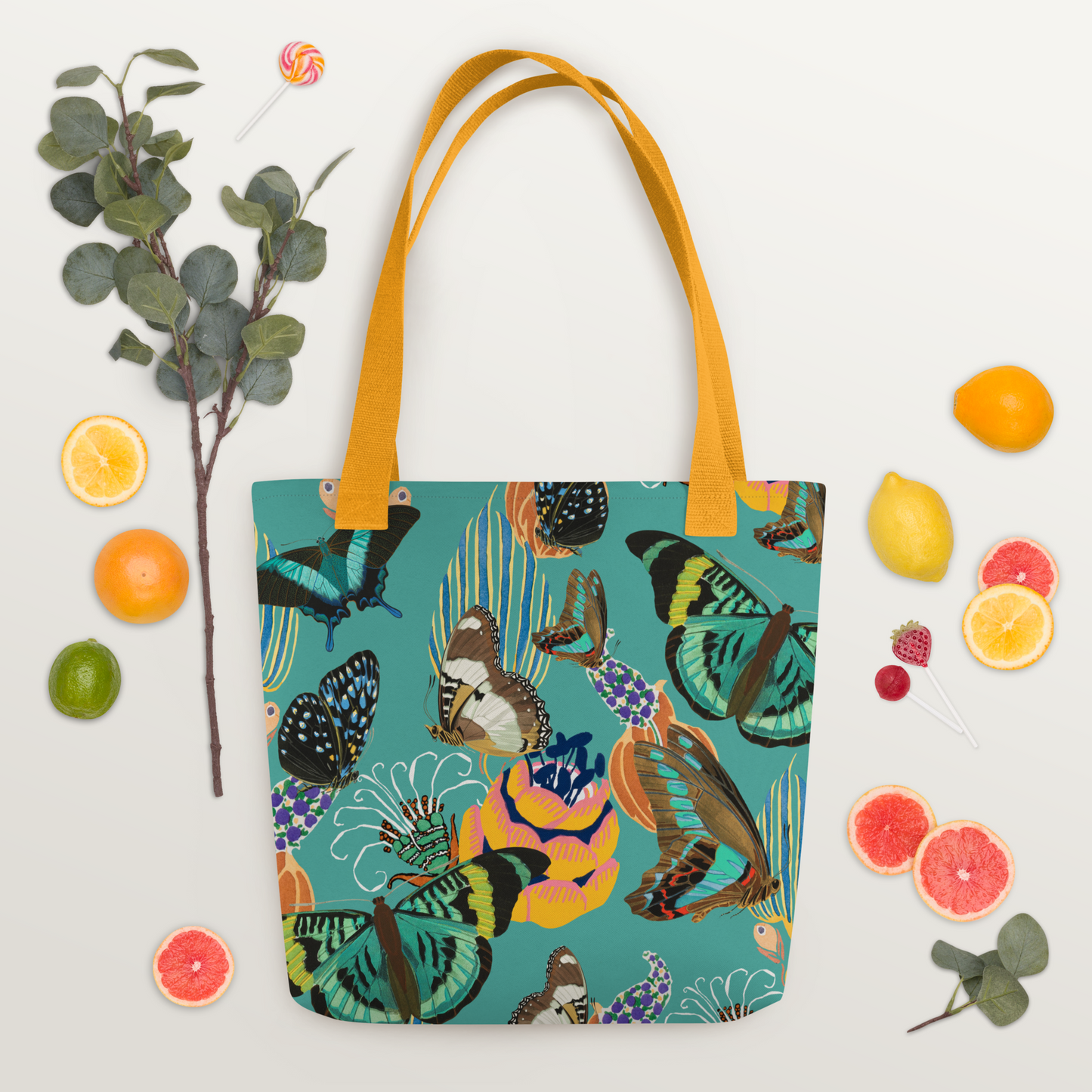 Tygväska i polyester med gula handtag och ett färgglatt all-over-mönster av fjärilar och blommor på turkos bakgrund.
Polyester tote bag with yellow handles and a vibrant all-over pattern of butterflies and flowers on a turquoise background.