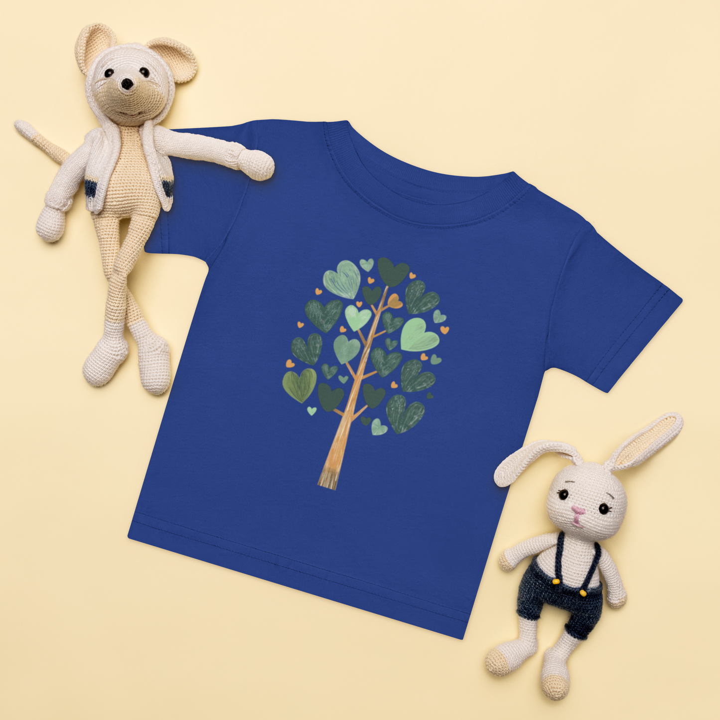 Baby-t-shirt i royalblå med ett träd av gröna hjärtan framtill.
Baby t-shirt in royal with a heart-shaped leaf tree illustration on the front.