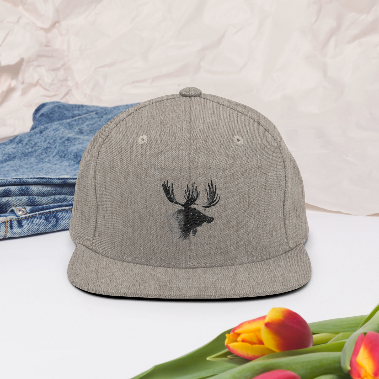 Melerad grå snapback-keps med broderat älghuvud i svart på framsidan.
Heather gray snapback cap, featuring an embroidered black moose head on the front.