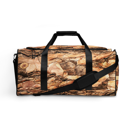Duffelväska i polyester med svart rem och ett detaljerat mönster som liknar trädbark i bruna och beige färger.
Polyester duffel bag with black strap and detailed pattern resembling tree bark in brown and beige tones.