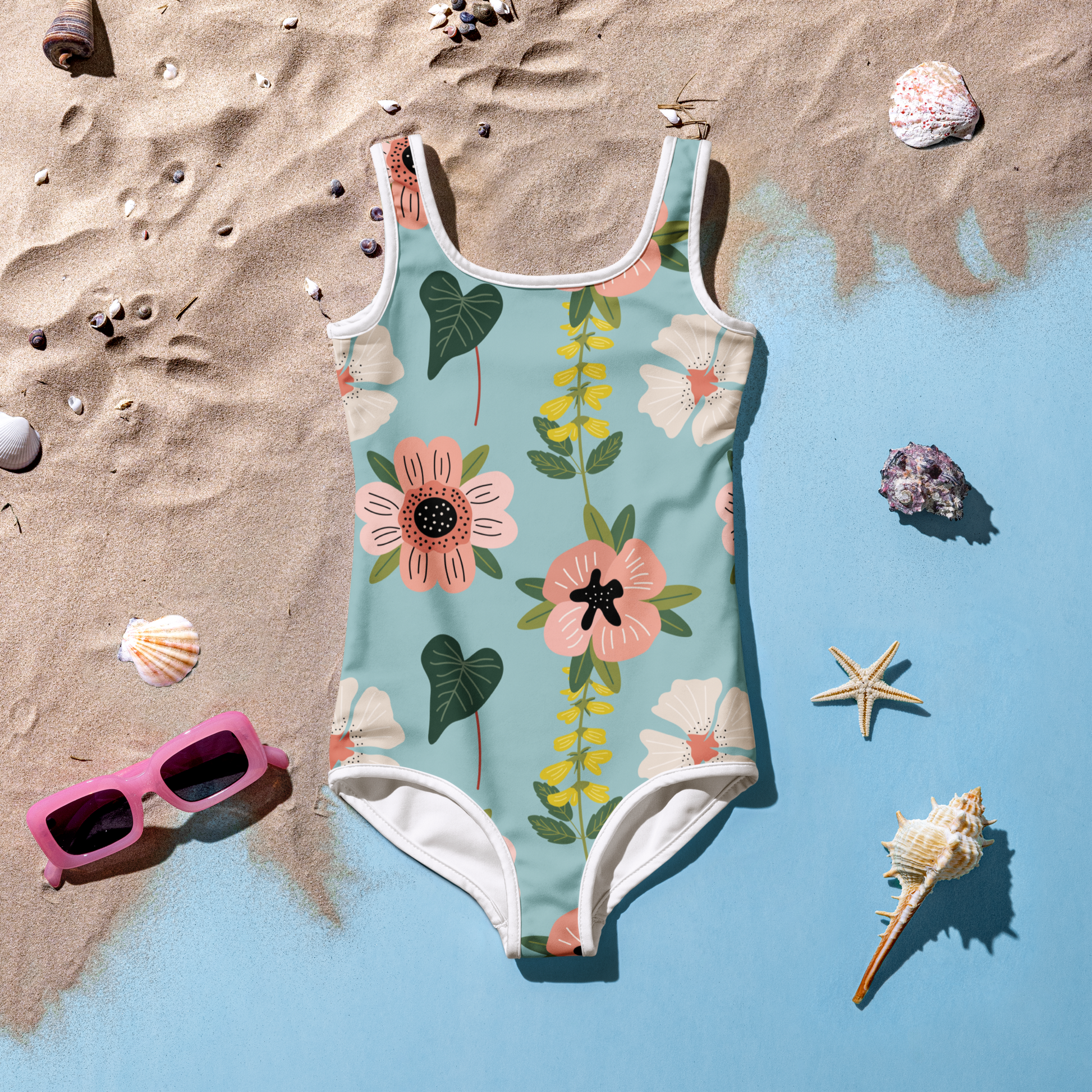 Flicka i blommig baddräkt med akvarellmönster i rosa, vitt och grönt mot blå bakgrund.
Girl in a floral swimsuit with a watercolor pattern in pink, white, and green against a blue background.