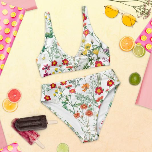 Högmidjad bikini i återvunnet material med färgglada ängsblommor på vit bakgrund.
High-waisted bikini made from recycled material with colorful meadow flowers on a white background.