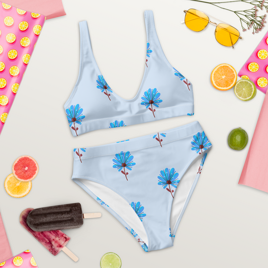 Högmidjad bikini i återvunnet material med handritade blå blommor på ljusblå bakgrund.
High-waisted bikini made from recycled material with hand-drawn blue flowers on a light blue background.


