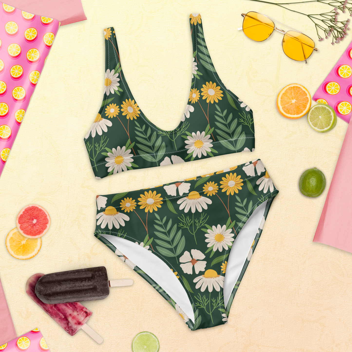 Återvunnen högmidjad bikini med handritade prästkragar och grön blommig bakgrund.
Recycled high-waisted bikini with hand-drawn daisies and a green floral background.