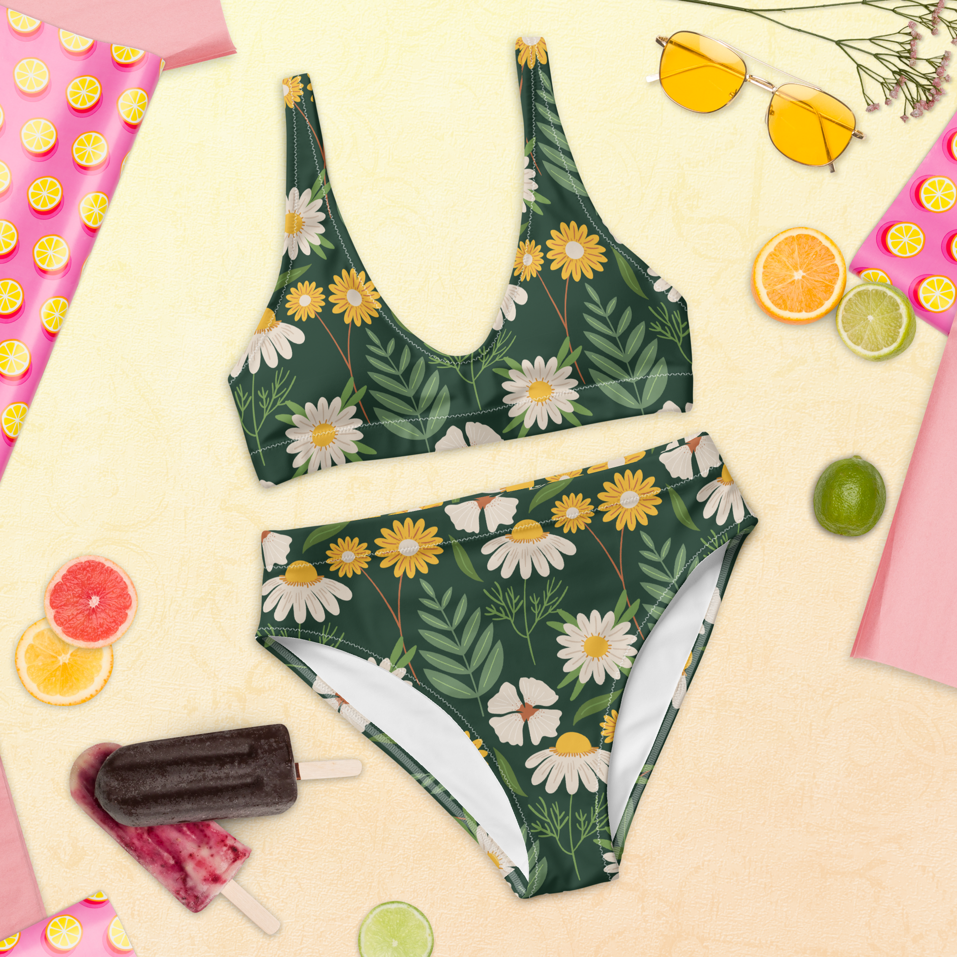 Återvunnen högmidjad bikini med handritade prästkragar och grön blommig bakgrund.
Recycled high-waisted bikini with hand-drawn daisies and a green floral background.