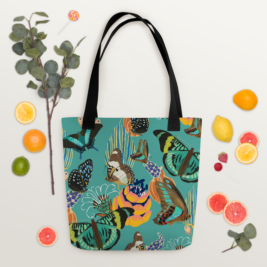 Tygväska i polyester med svarta handtag och ett färgglatt all-over-mönster av fjärilar och blommor på turkos bakgrund.
Polyester tote bag with black handles and a vibrant all-over pattern of butterflies and flowers on a turquoise background.