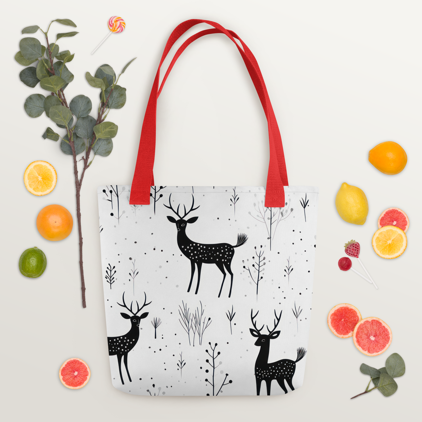 Vit polyester-tygväska med rött handtag och svartvitt mönster av hjortar och växtmotiv över hela ytan.
White polyester tote bag with red handle and black-and-white deer and foliage pattern printed all over.