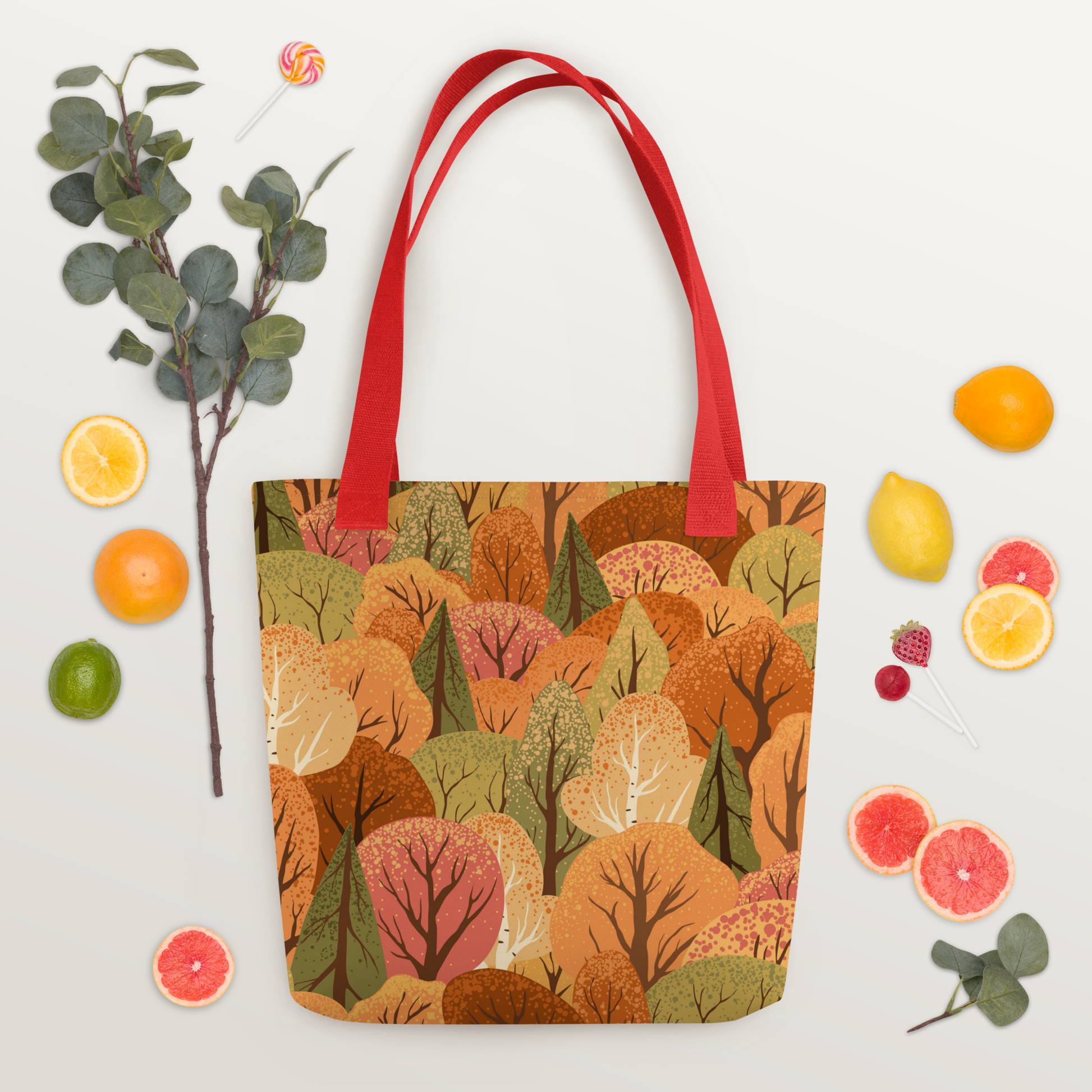 Polyester-tygväska med rött handtag och mönster av stiliserade träd i höstens färger – orange, rött, gult och grönt.
Polyester tote bag with red handle and a stylized pattern of autumn-colored trees in orange, red, yellow, and green.