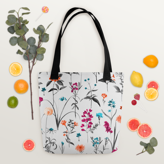 Vit polyester tygväska med svarta handtag och färgglada blommor i orange, rosa, turkos och lila på hela ytan.
White polyester tote bag with black handles and colorful flowers in orange, pink, turquoise, and purple across the surface.