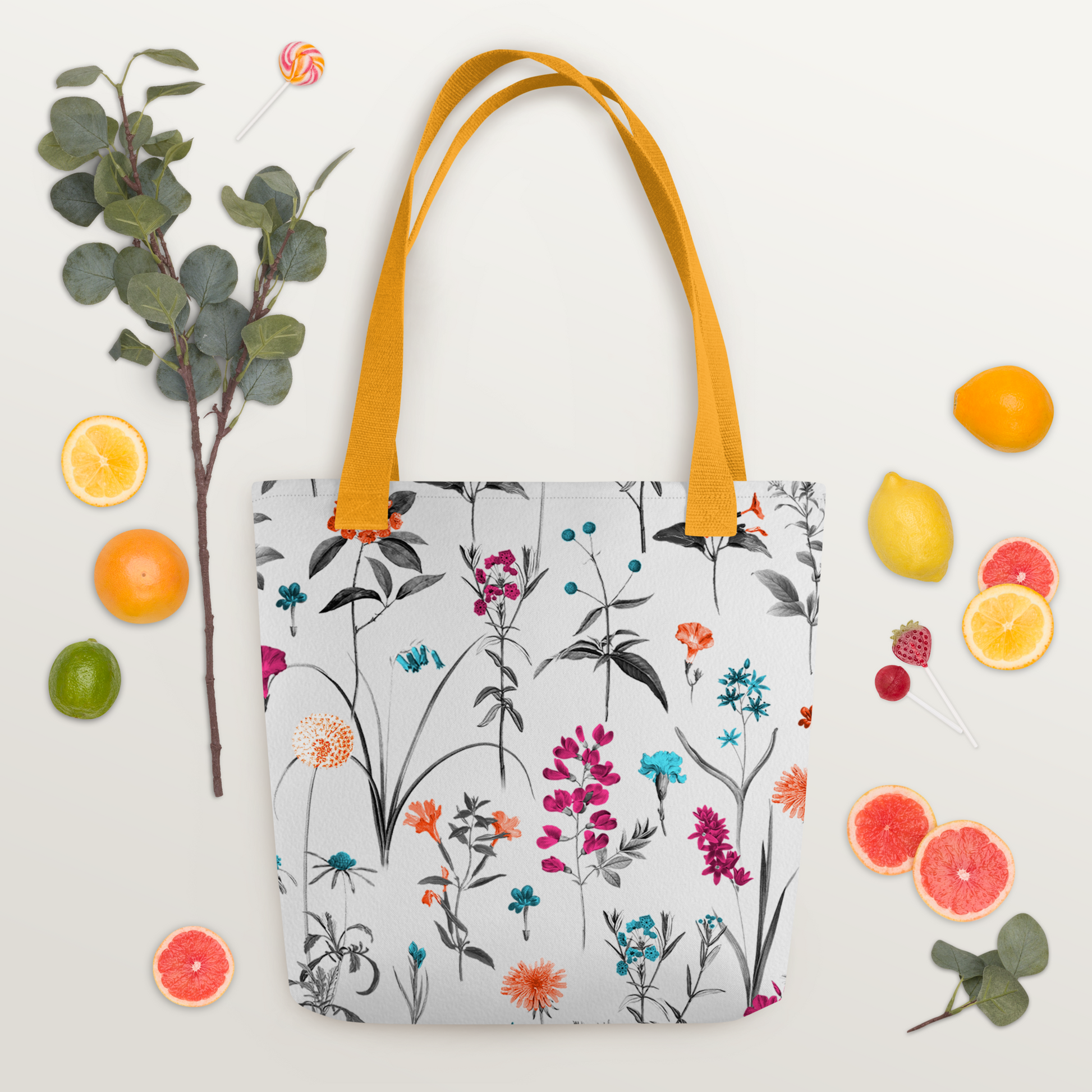 Vit polyester tygväska med gula handtag och färgglada blommor i orange, rosa, turkos och lila på hela ytan.
White polyester tote bag with yellow handles and colorful flowers in orange, pink, turquoise, and purple across the surface.