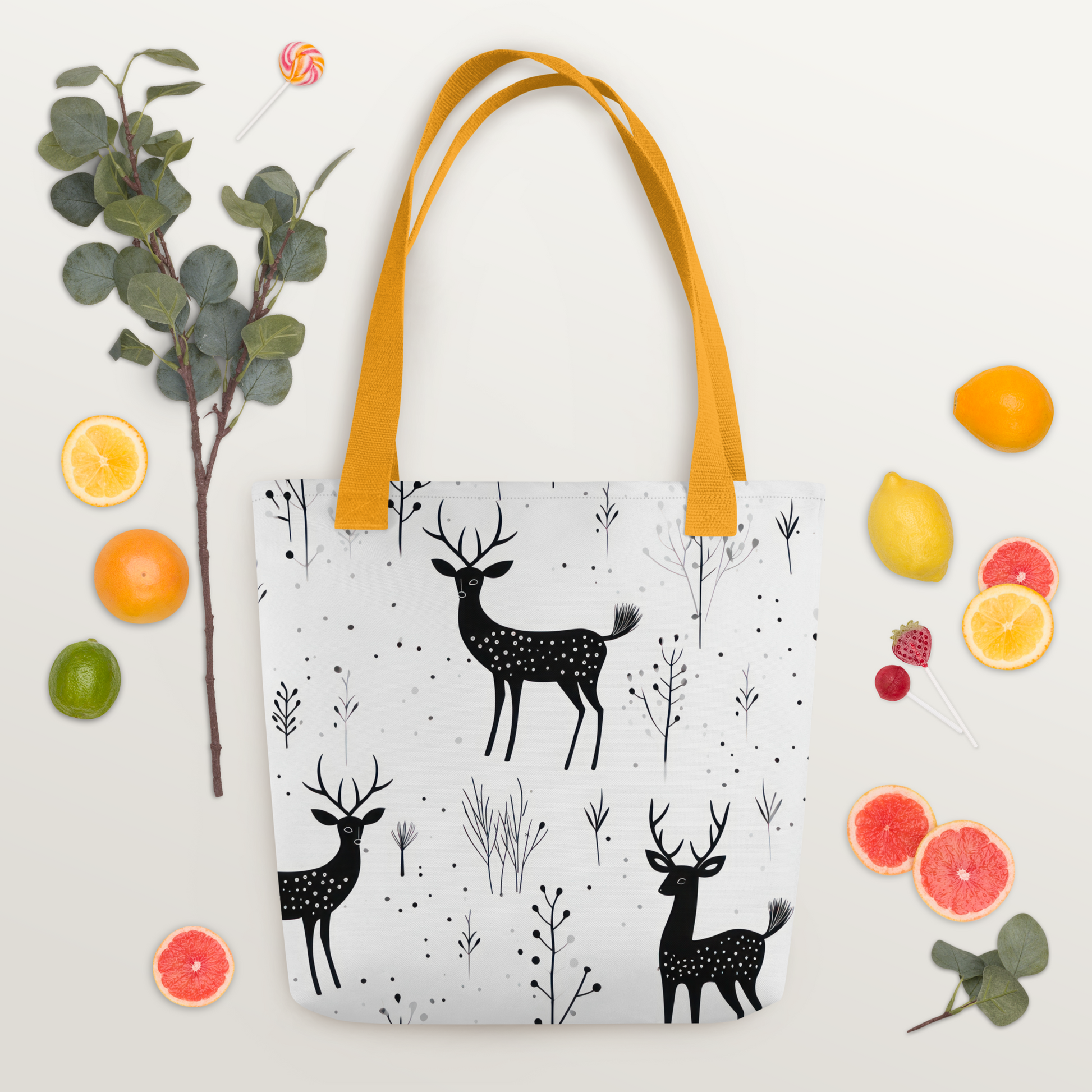 Vit polyester-tygväska med gult handtag och svartvitt mönster av hjortar och växtmotiv över hela ytan.
White polyester tote bag with yellow handle and black-and-white deer and foliage pattern printed all over.