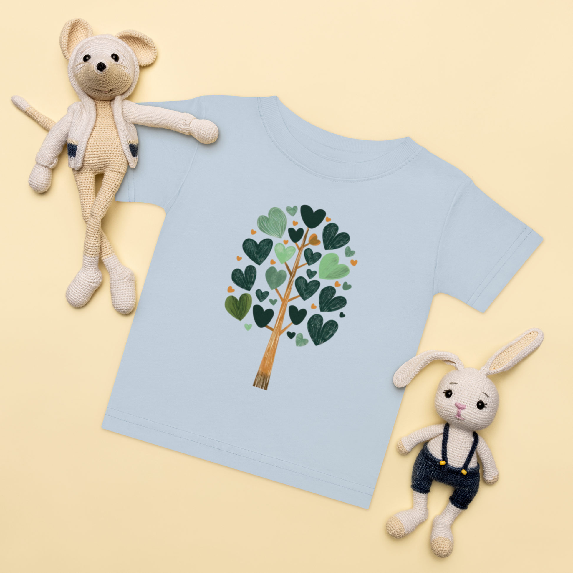 Baby-t-shirt i ljusblå med ett träd av gröna hjärtan framtill.
Baby t-shirt in light blue with a heart-shaped leaf tree illustration on the front.