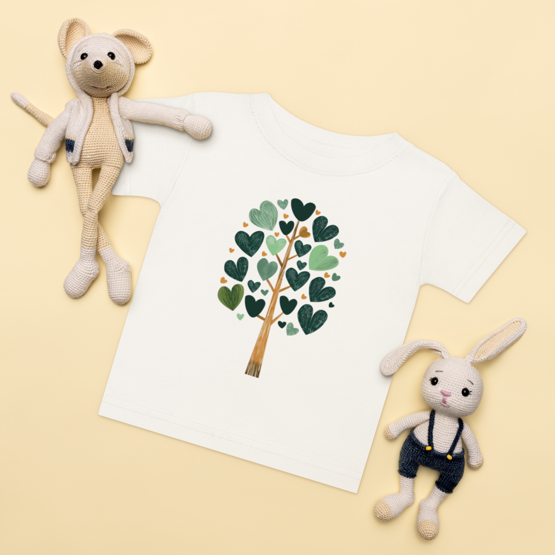 Baby-t-shirt i vit med ett träd av gröna hjärtan framtill.
Baby t-shirt in white with a heart-shaped leaf tree illustration on the front.