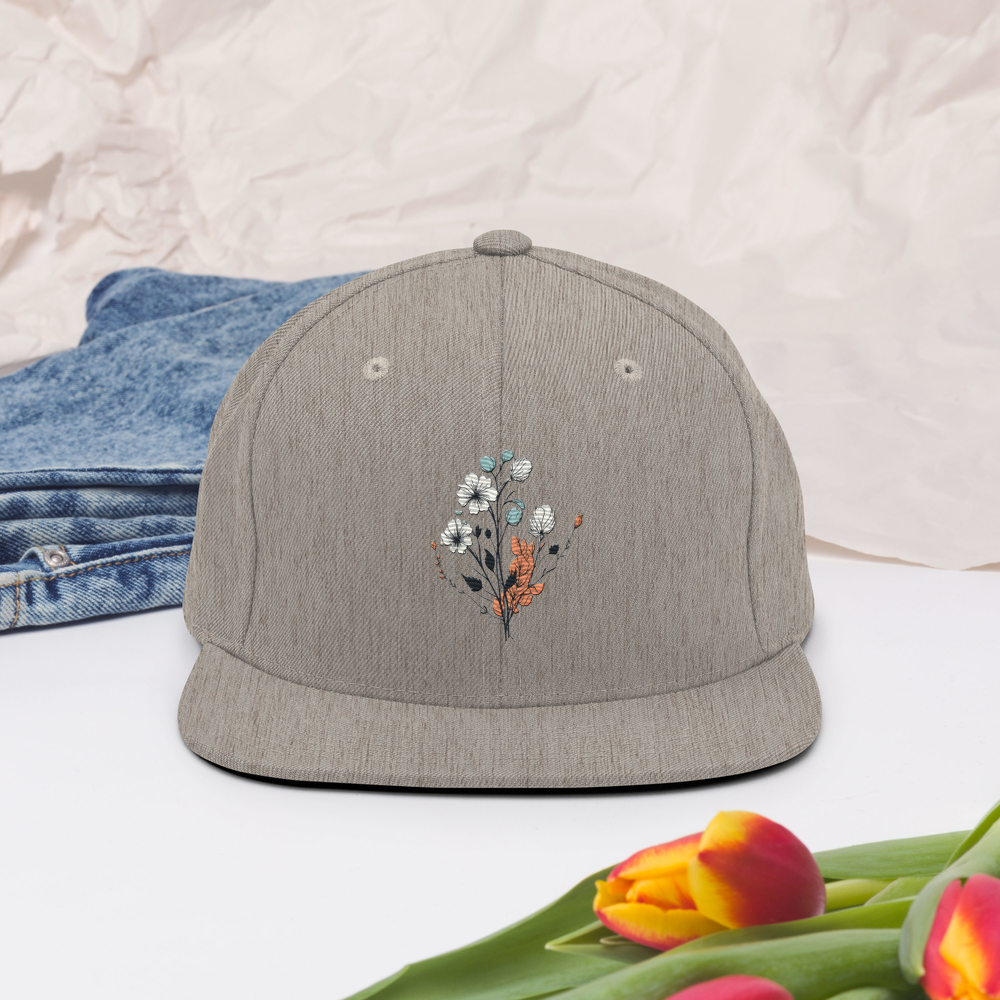 Melerad grå snapback keps med broderad blomdesign framtill
Heather grey snapback cap with embroidered floral design on the front.