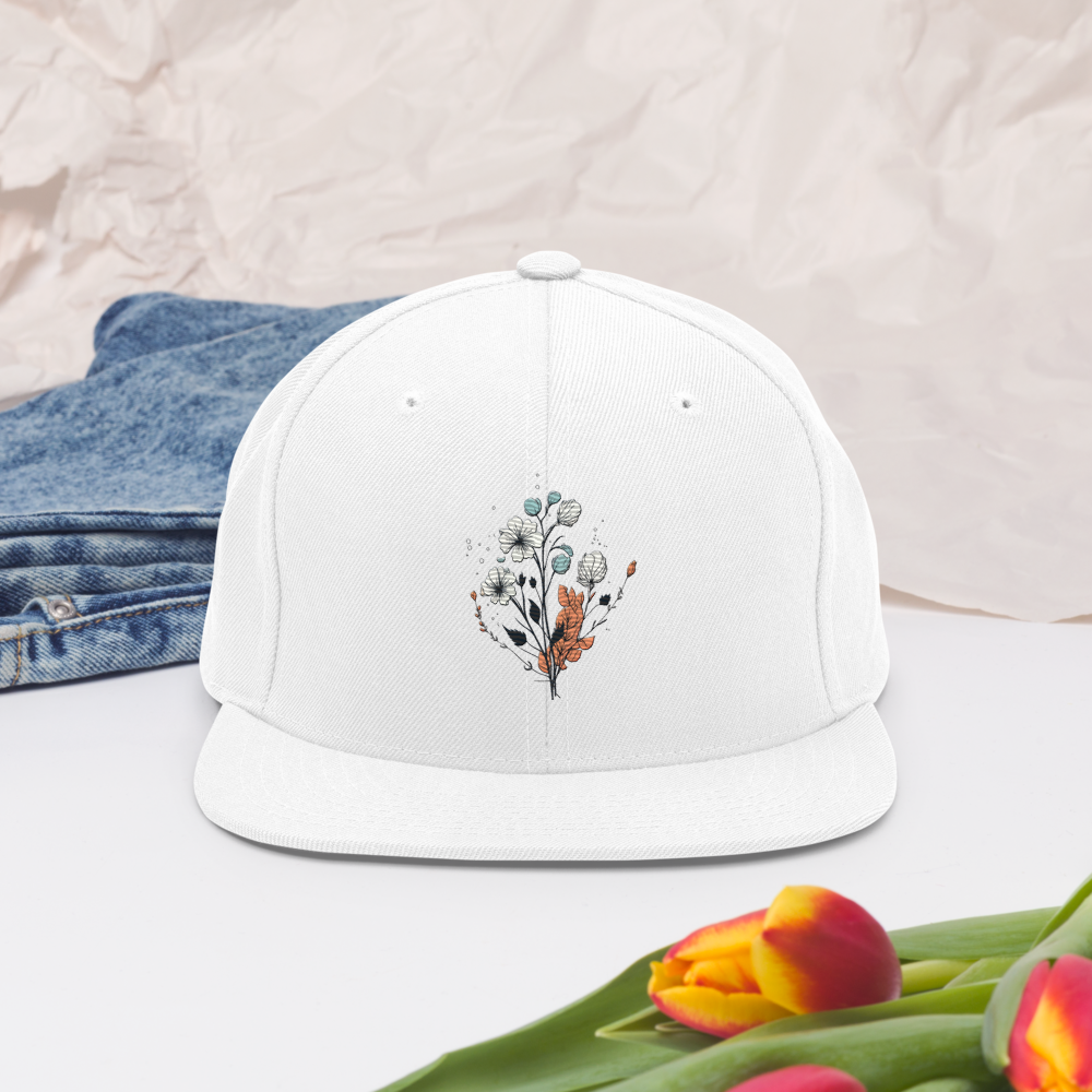 Vit snapback keps med broderad blomdesign framtill.
White snapback cap with embroidered floral design on the front.