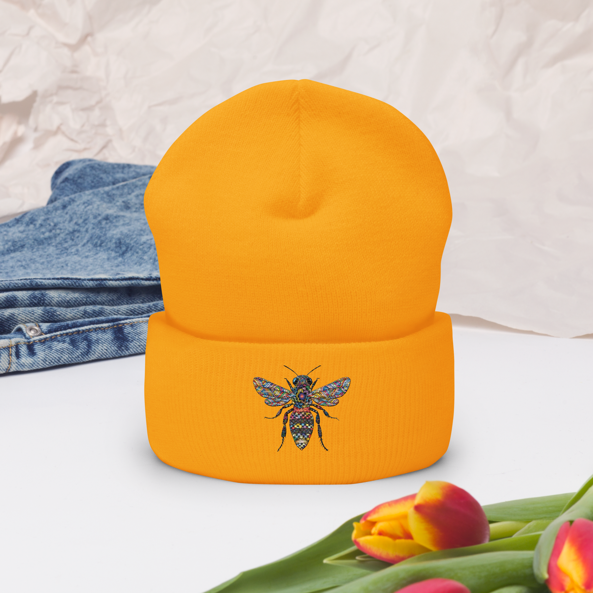 Orange uppvikt mössa med broderad bi i flerfärg framtill.
Orange cuffed beanie with multicolored embroidered bee on the front.
