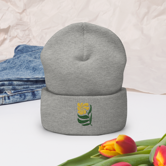 Grå uppvikt mössa med broderad gul blomma och gröna blad framtill.
Grey cuffed beanie with embroidered yellow flower and green leaves on the front.