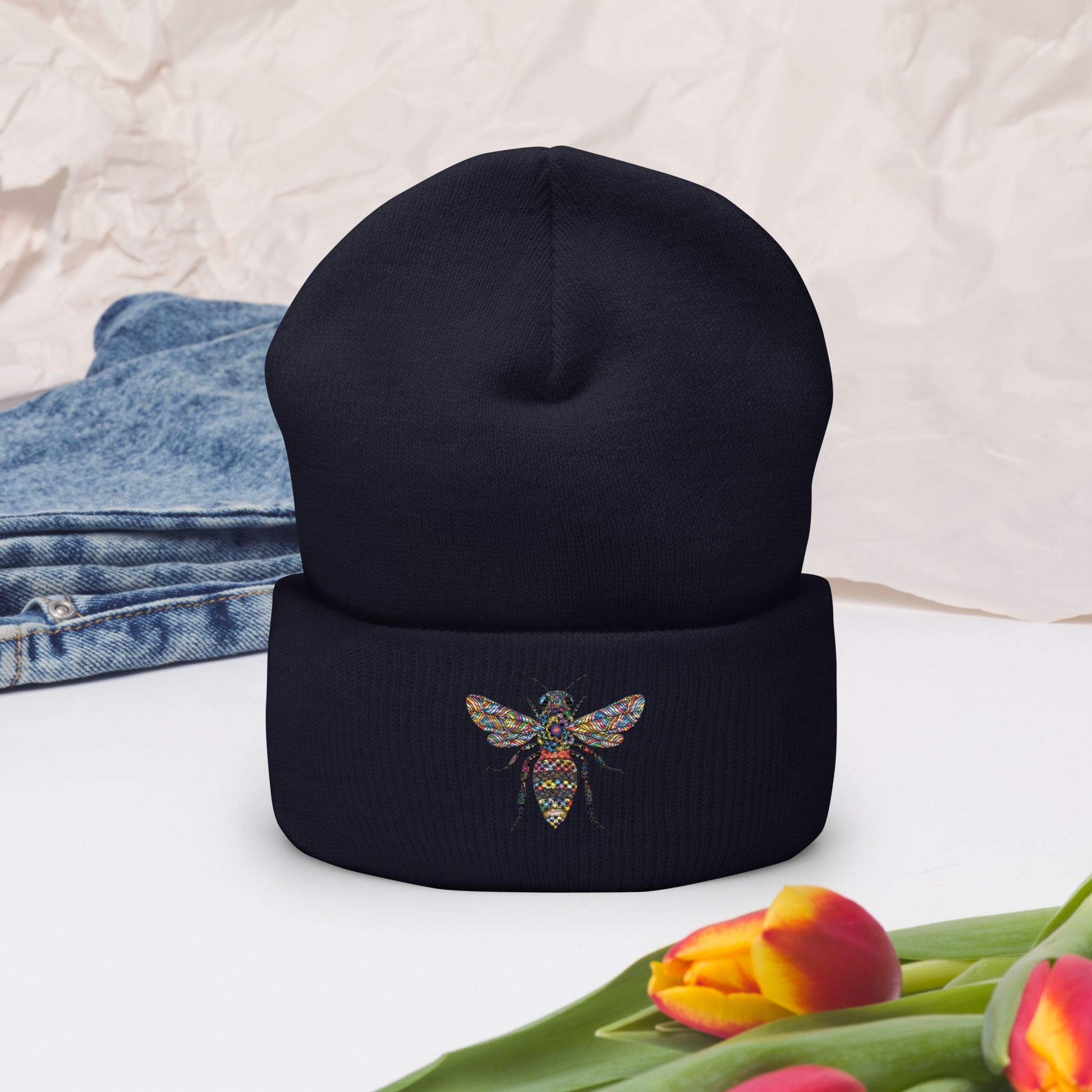 Marinblå uppvikt mössa med broderad bi i flerfärg framtill.
Navy cuffed beanie with multicolored embroidered bee on the front.