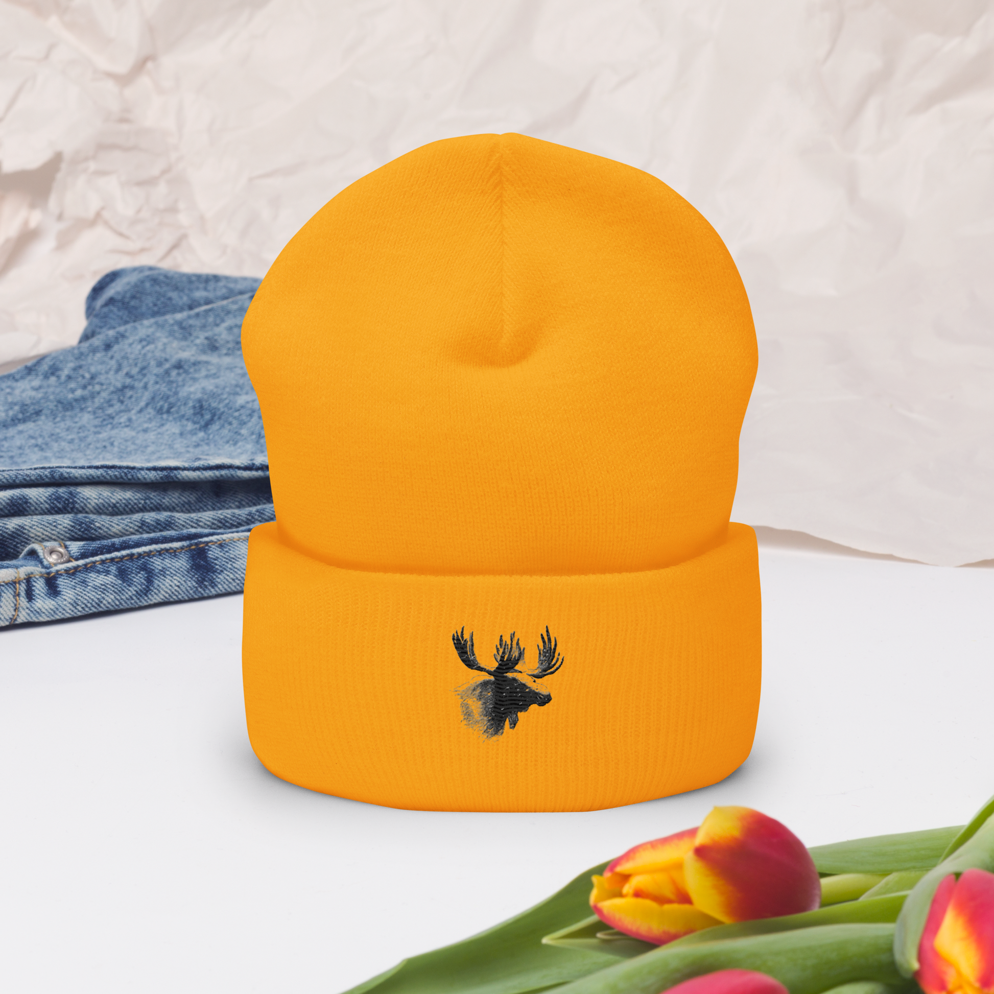 Orange uppvikt mössa med broderat älghuvud i svart framtill.
Orange cuffed beanie with black embroidered moose head on the front.