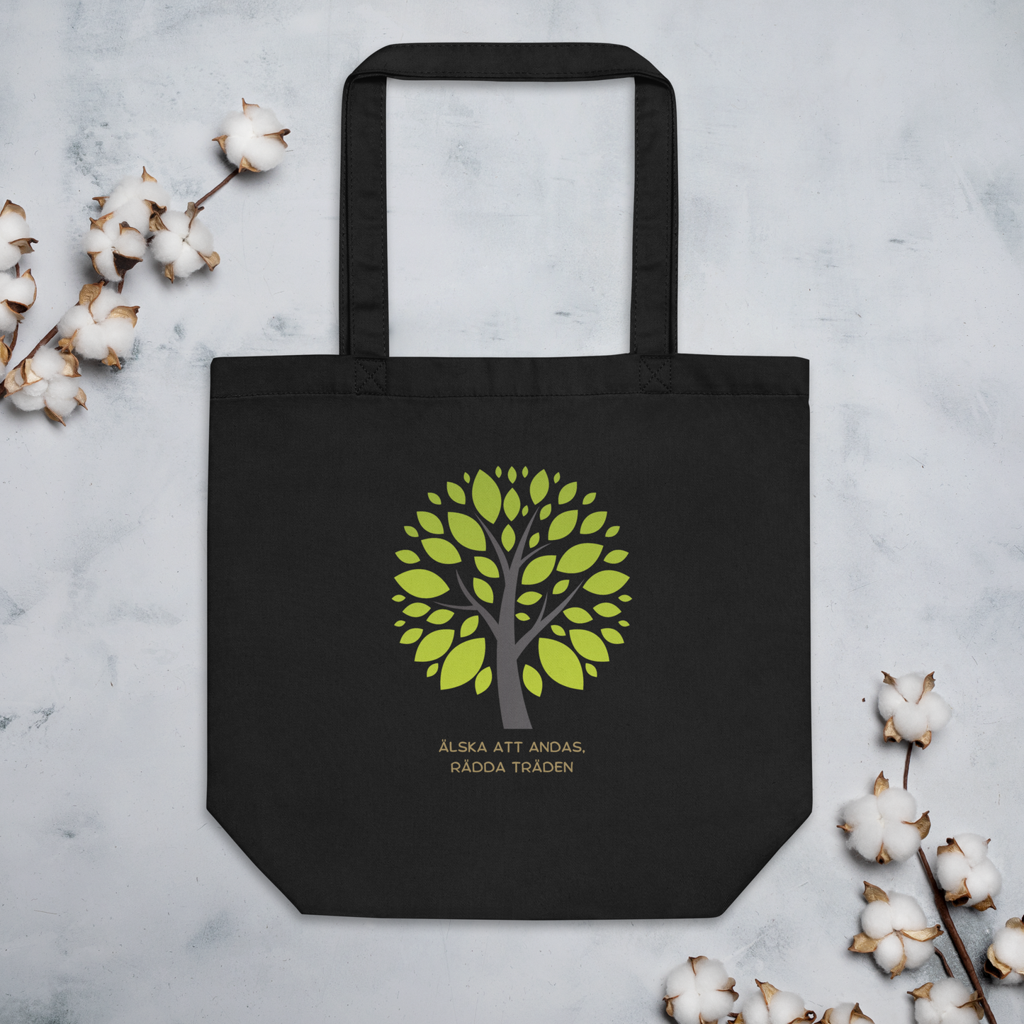Svart ekologisk tygväska med grönt trädmotiv och texten "Älska att andas, rädda träden" under trädet.
Black eco tote bag with a green tree design and the text "Älska att andas, rädda träden" under the tree.