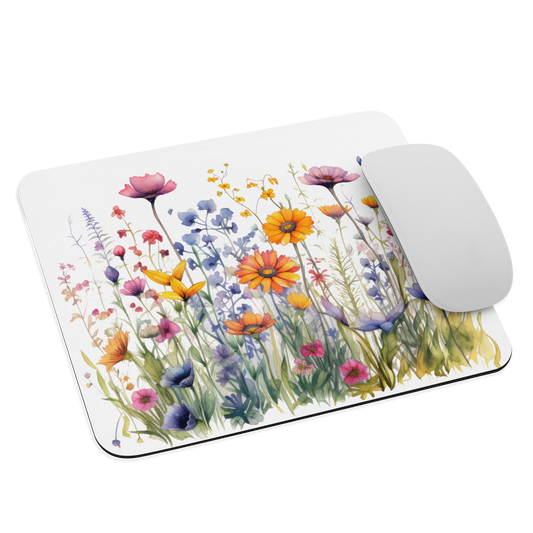 Musmatta med akvarellmotiv av vilda blommor i olika färger mot vit bakgrund.
Mouse pad featuring a watercolor design of colorful wildflowers on a white background.