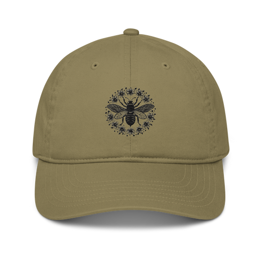 Ekologisk baseballkeps i färgen djungelgrön med broderat bimotiv i svart, föreställande en stor bi av små blommor i cirkelmönster på framsidan.
Organic jungle green baseball cap with a black embroidered bee design featuring a large central bee surrounded by flowers in a circular pattern on the front.