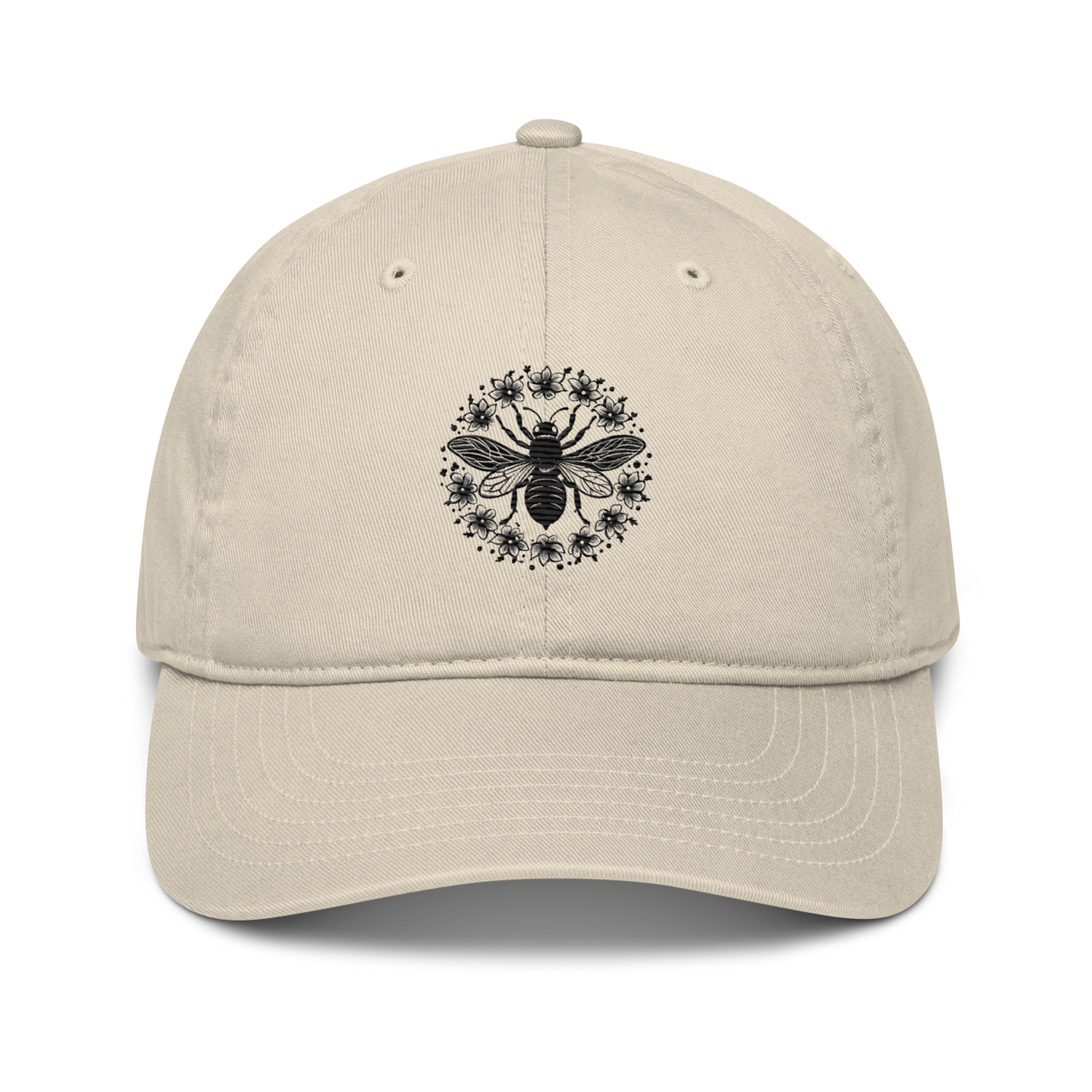 Ekologisk baseballkeps i färgen ljusbeige med broderat bimotiv i svart, föreställande en stor bi av små blommor i cirkelmönster på framsidan.
Organic oyster baseball cap with a black embroidered bee design featuring a large central bee surrounded by flowers in a circular pattern on the front.