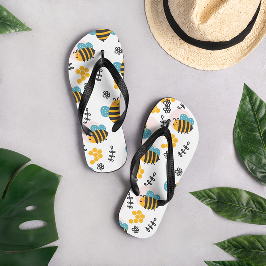 Flip-flops med färgglatt bimönster, blommor och honungskakor på vit bakgrund.
Flip-flops with colorful bee pattern, flowers, and honeycombs on a white background.