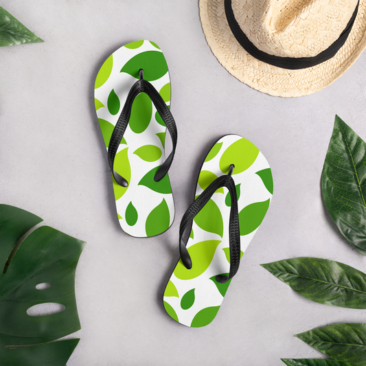 Flip-flops med grönt lövmönster på vit bakgrund.
Flip-flops with a green leaf pattern on a white background.
