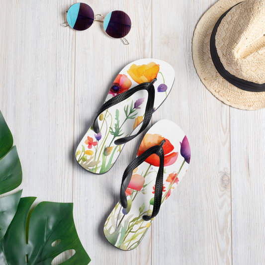 Färgglada flip-flops med blommotiv i akvarellstil och svarta Y-formade remmar.
Colorful flip-flops with a watercolor floral pattern and black Y-shaped straps