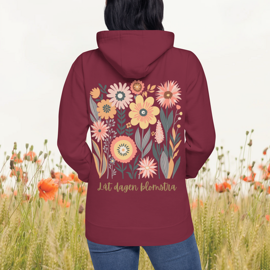 Vinrött unisex premium hoodie med färgglad blommotiv och texten "Låt dagen blomstra!". Maroon unisex premium hoodie with colorful floral motif and the text "Låt dagen blomstra!".