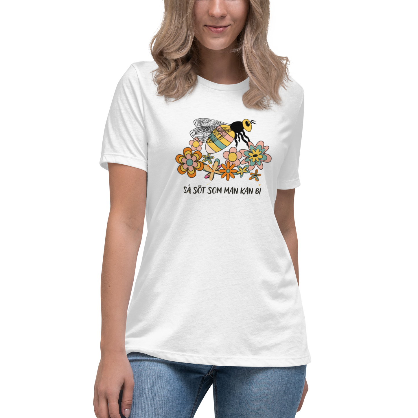 Vit avslappnad t-shirt med en handritad bi och färgglada blommor samt texten “Så söt som man kan bi”.
White relaxed t-shirt with a hand-drawn bee, colorful flowers, and the text “As sweet as can bee”.
