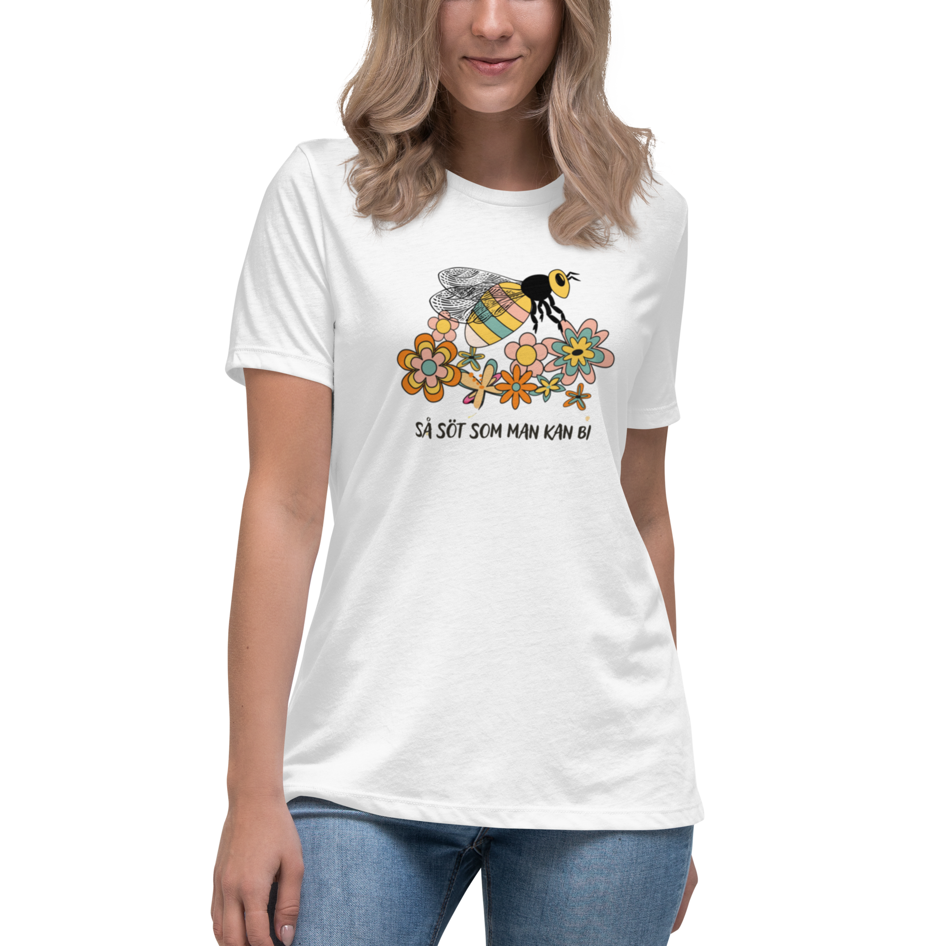 Vit avslappnad t-shirt med en handritad bi och färgglada blommor samt texten “Så söt som man kan bi”.
White relaxed t-shirt with a hand-drawn bee, colorful flowers, and the text “As sweet as can bee”.