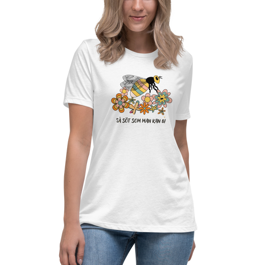Vit avslappnad t-shirt med en handritad bi och färgglada blommor samt texten “Så söt som man kan bi”.
White relaxed t-shirt with a hand-drawn bee, colorful flowers, and the text “As sweet as can bee”.